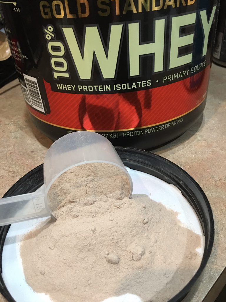 highest rated protein powders: Tub and Scoop of Chocolate Whey Protein Powder